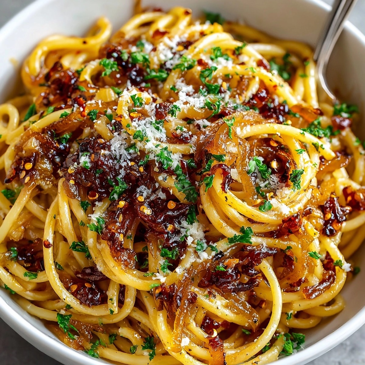 Caramelized onion pasta with chilli oil glistens under a sprinkle of fresh parsley and Parmesan.