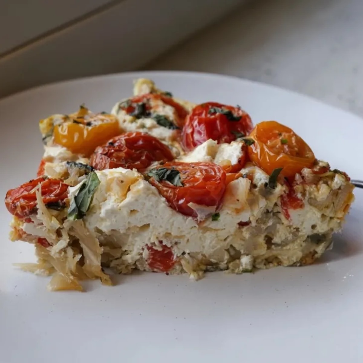 Close-up of a Ricotta Tomato Basil Frittata in a skillet, golden brown and bubbly.