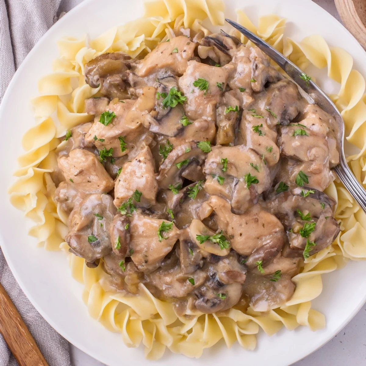 Creamy Chicken Stroganoff served over egg noodles, garnished with fresh parsley.  
