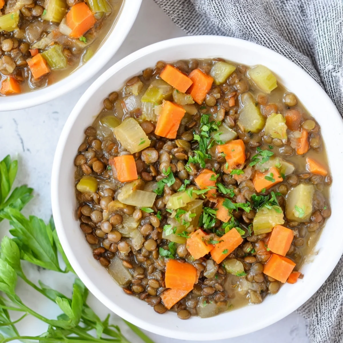Bright orange Lentil Soup, seasoned perfectly, in a rustic bowl, alongside fresh lemon wedges.