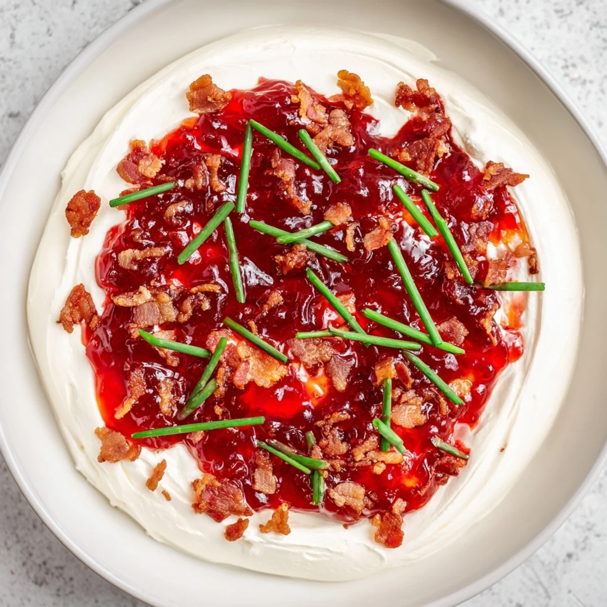 A beautiful serving dish of Easy Bacon Pepper Jelly, featuring chopped bacon and green chives, is perfect for sharing.