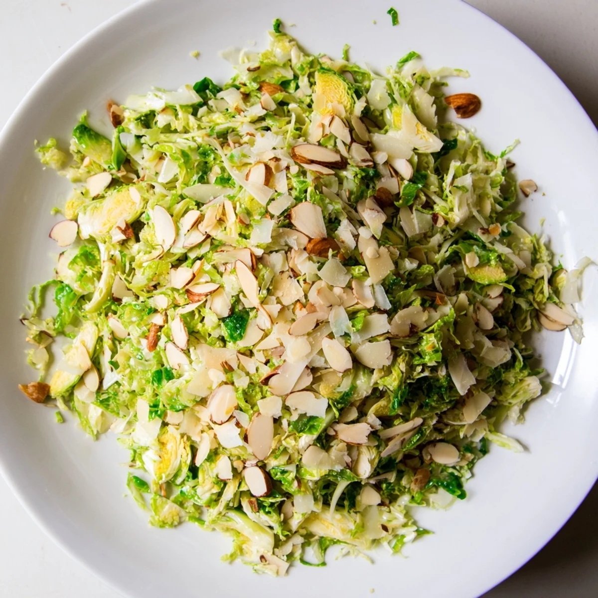 Vibrant Crunchy Lemon Parmesan Brussels Sprouts Salad topped with toasted almonds and fresh Parmesan cheese.