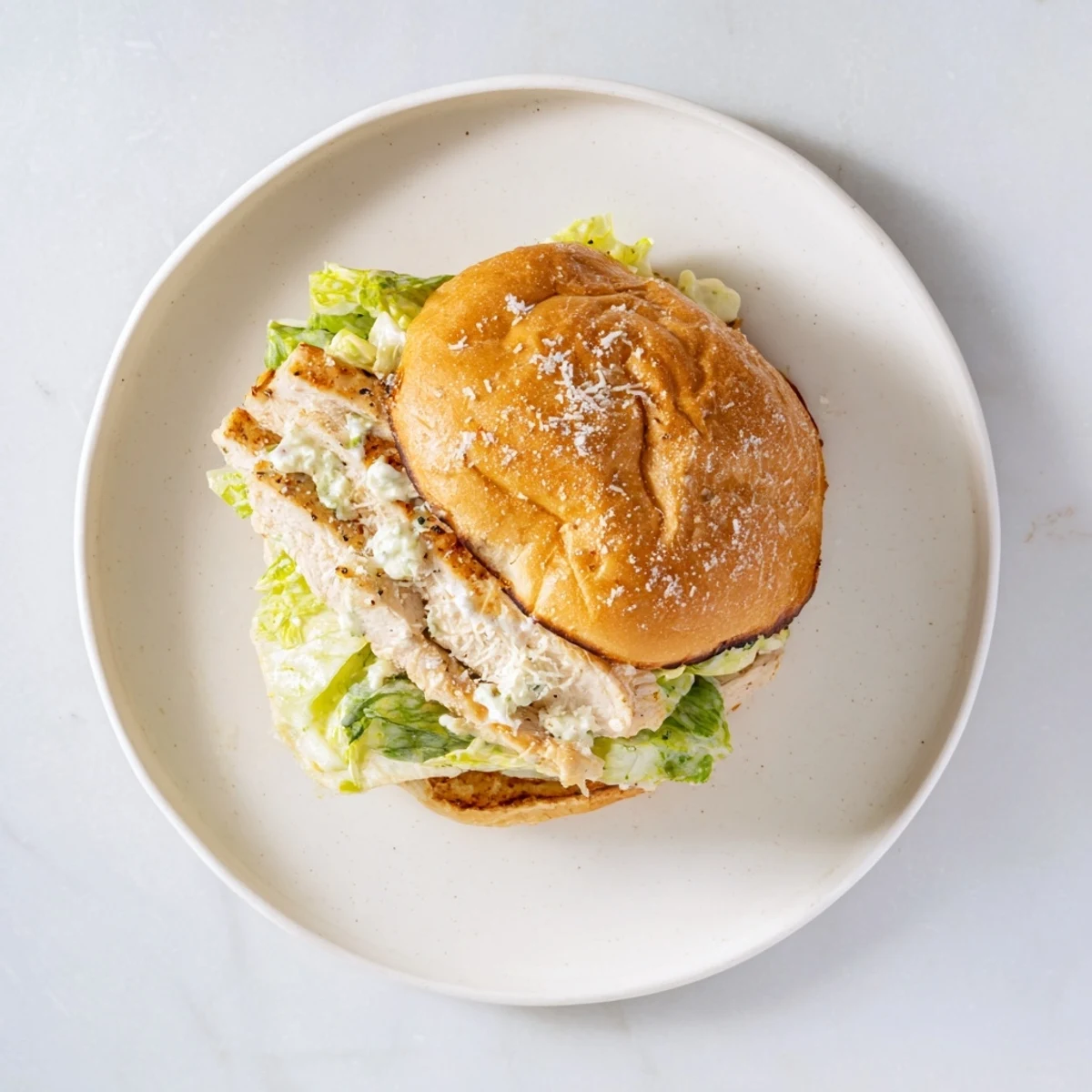 Freshly grilled Caesar Chicken Sandwich ready to serve, featuring melted Parmesan and a drizzle of extra creamy Caesar dressing.  