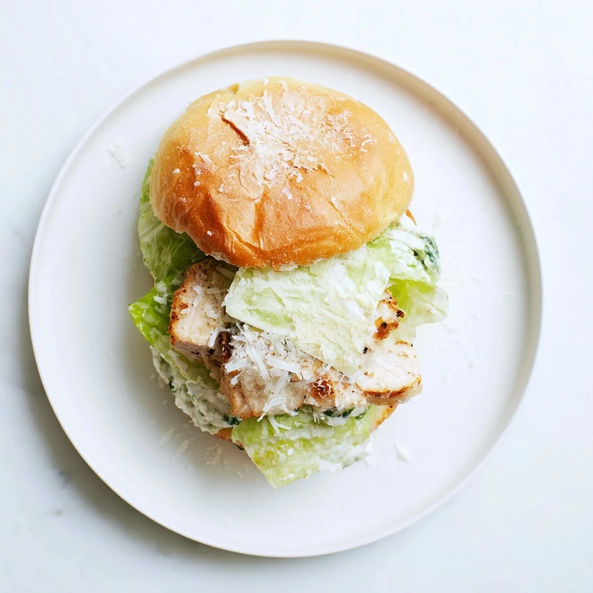 A close-up of a Caesar Chicken Sandwich, highlighting the tender chicken breast nestled between crunchy romaine and soft brioche.