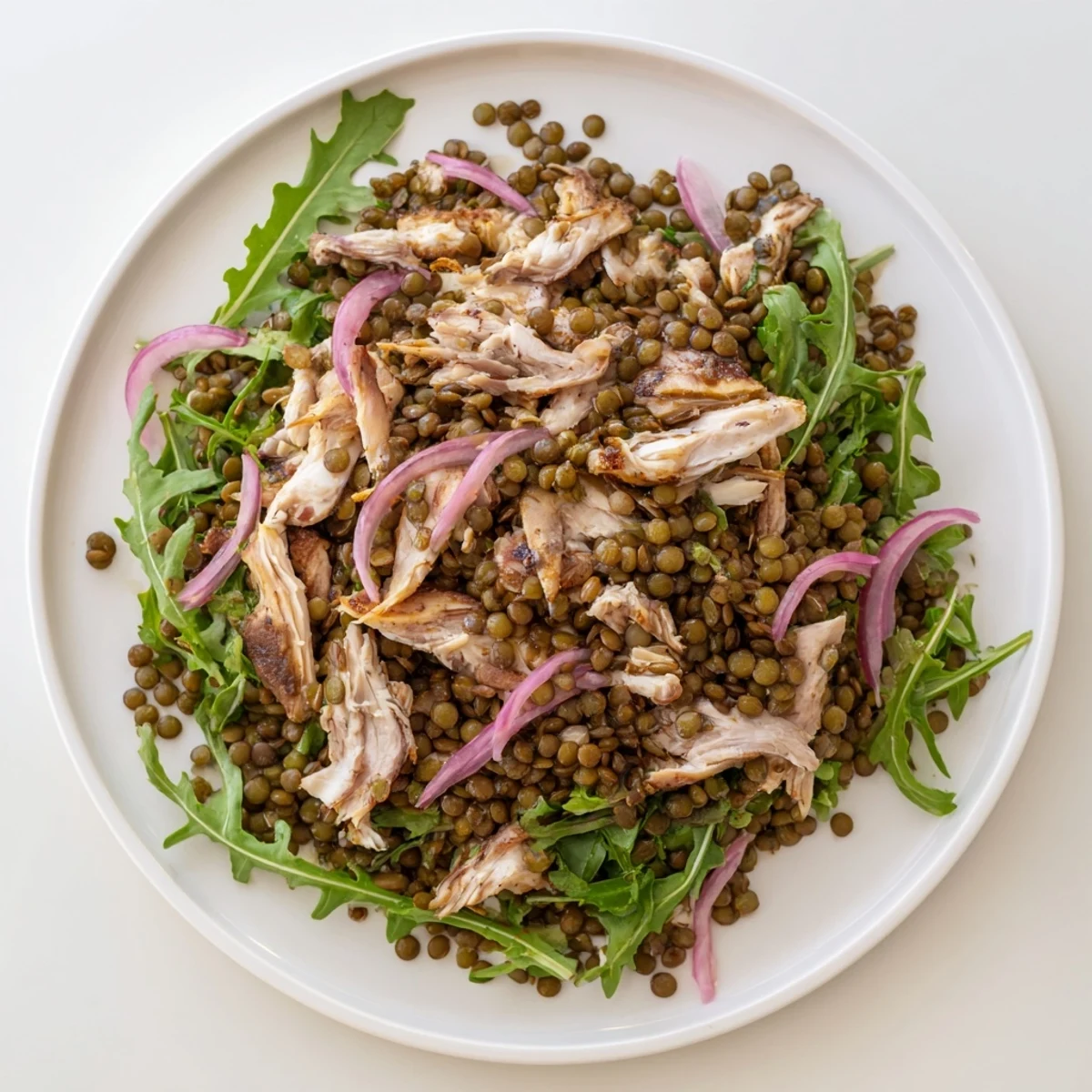 A close-up of the Lentil & Chicken Spring Salad, showcasing tender lentils, juicy shredded chicken, and vibrant arugula in a zesty mustard dressing.