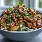 A close-up of tender chicken and crisp cabbage in a savory Egg Roll Bowls with Chicken and Cabbage recipe, drizzled in tangy soy-sesame glaze.