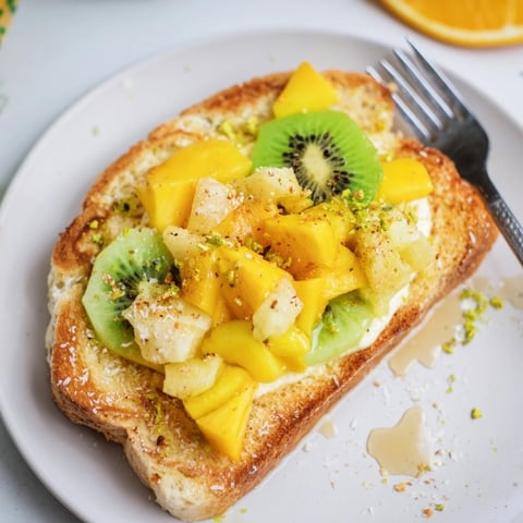 Delicious yogurt-custard toast topped with vibrant tropical fruits for breakfast bliss.  