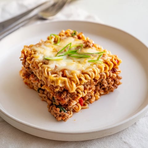 Spicy Ramen Lasagna with layers of savory pork, creamy cheese, and vibrant sauce. 
