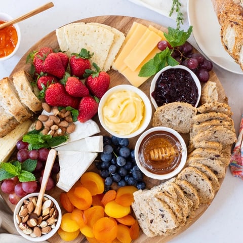 A colorful jam-infused brunch board featuring fresh fruits and artisan cheeses.  