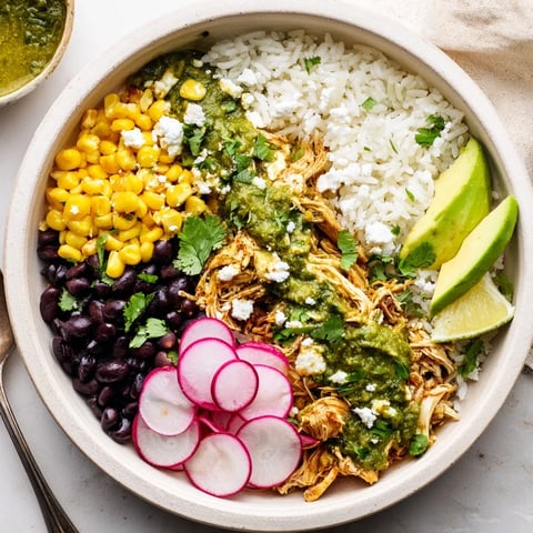 Vibrant green enchiladas rice bowl topped with avocado and fresh cilantro sprigs.  