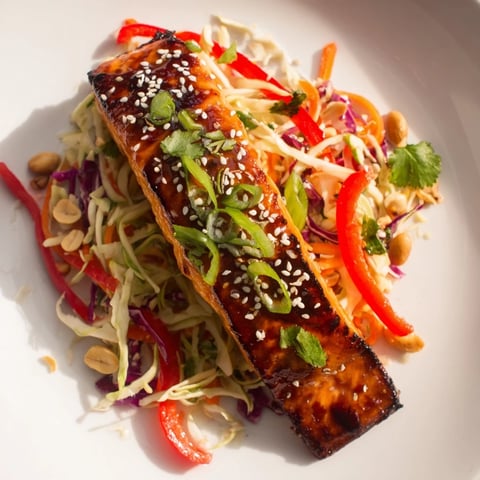 Golden-brown teriyaki salmon glistens atop a crunchy Asian slaw in this colorful bowl.