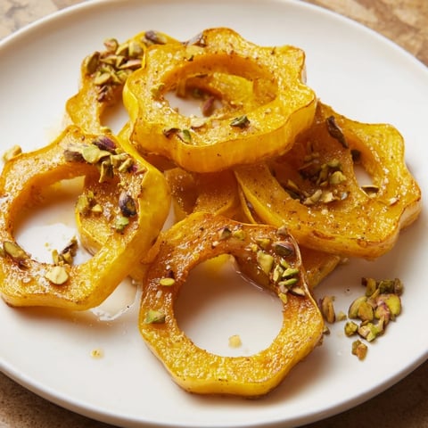 Golden baked delicata squash rings glistening with maple glaze and sprinkled with bright pistachios.