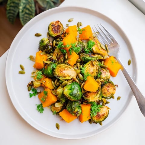 Golden-brown roasted Brussels sprouts and butternut squash with bright orange dressing, ready for serving.