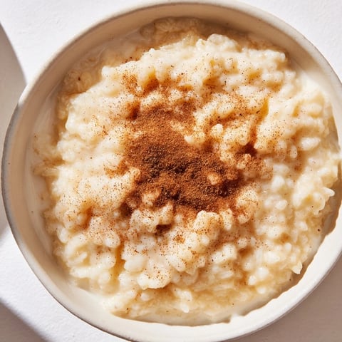 A bowl of warm Rice Pudding with Leftover Rice, dusted with cinnamon, is a comforting treat.