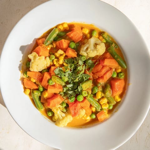 A steaming bowl of Veggie Coconut Curry, vibrant with tender vegetables and creamy coconut milk.