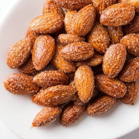 Golden, glistening cinnamon roasted almonds piled on parchment, ready to eat and share.