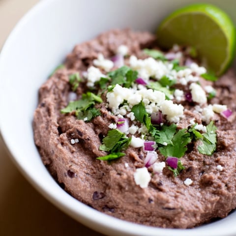 Creamy Spicy Black Bean Dip, garnished with cilantro, ready to scoop with crunchy tortilla chips.