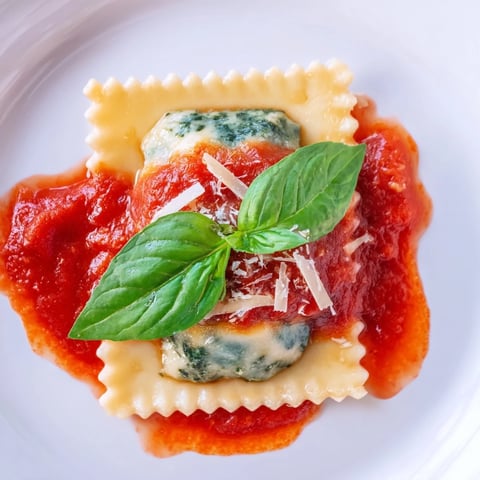 Homemade Spinach Ricotta Ravioli in a rich, chunky marinara sauce, garnished with fresh basil and grated Parmesan.