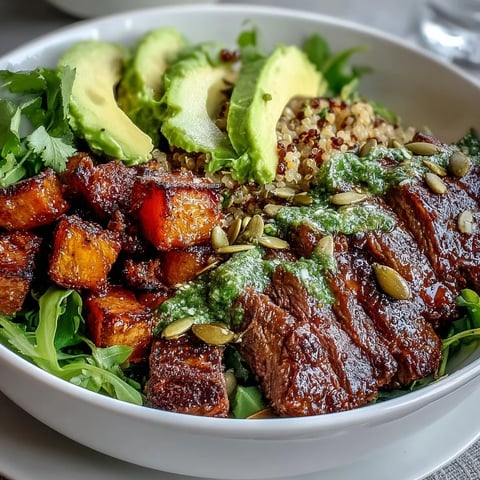 Roasted butternut squash steak bowls feature smoky sliced steak and creamy avocado on fluffy quinoa, drizzled with a zesty lime-cilantro dressing.
