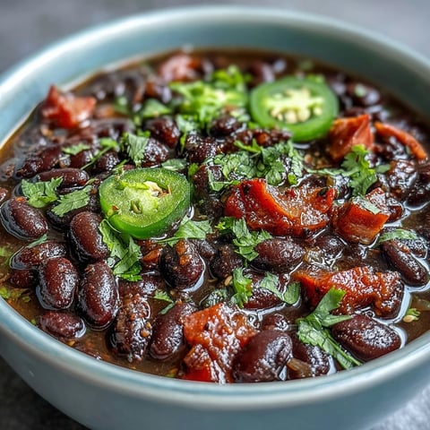 A steaming bowl of Black Bean and Ham Soup with jalapeños, topped with fresh cilantro and lime wedges.