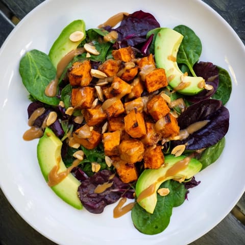Warm roasted sweet potatoes in a Spiced Peanut Sweet Potato Salad Bowl with vibrant, fresh ingredients.