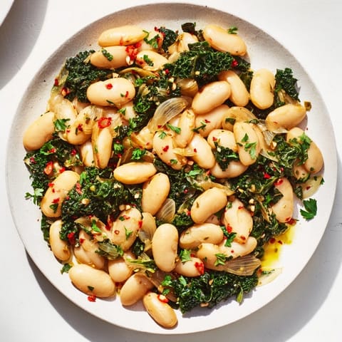Rustic Garlicky Beans with Winter Greens, a delicious vegan dish served in a warm bowl with fresh parsley.