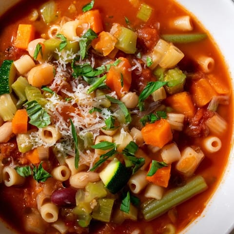Warm, vibrant, close-up of tomato basil minestrone, ready to be enjoyed with crusty bread.