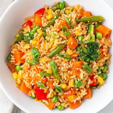 Golden-brown Vegetable Fried Rice, garnished with green onions and sesame seeds, ready to serve hot.