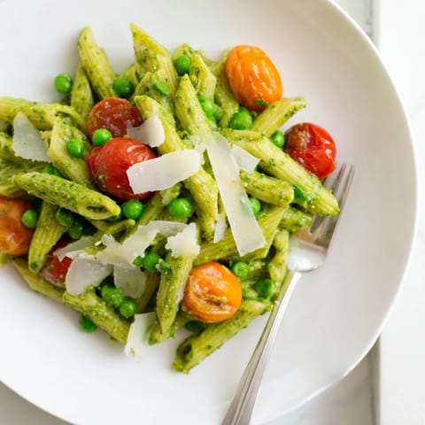Green Pesto Pasta Salad served as a refreshing main dish, garnished with fresh basil leaves.  