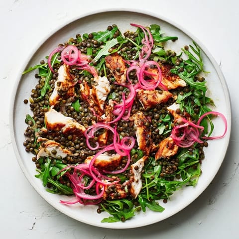 Freshly tossed Lentil & Chicken Spring Salad in a white bowl, with pickled red onions, cherry tomatoes, and a light vinaigrette glazing the greens.