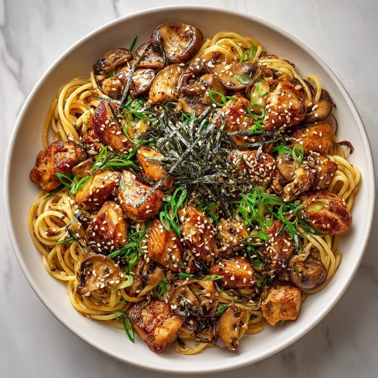 Close-up of flavorful teriyaki chicken pasta, topped with sake-glazed shiitake mushrooms and fresh spring onions.
